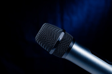 Close-up of microphone in studio or concert performance on stage, on black background.