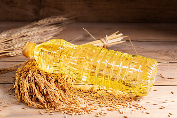 Vegetable oil extracted from rice seeds is packed in glass or plastic bottles with golden yellow rice seeds, which are an agricultural product, top view