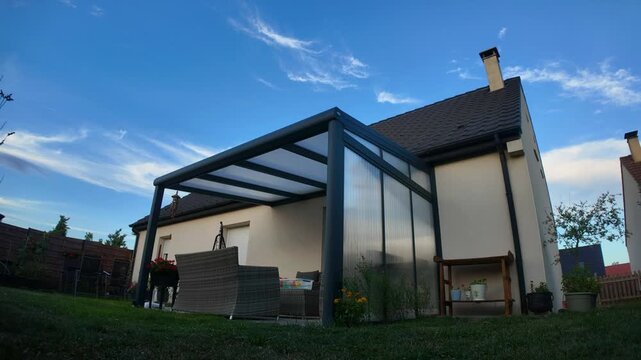 A timelapse of clouds moving over a modern backyard patio with a pergola
