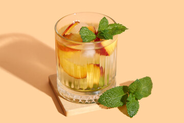 Glass of fresh peach lemonade with mint on orange background, closeup