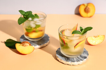 Glasses of fresh peach lemonade with mint on orange table, closeup