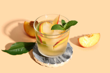 Glass of fresh peach lemonade with mint on orange background