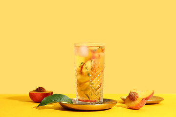 Glass of fresh peach lemonade with thyme on yellow background