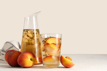 Glass and jug of fresh peach lemonade with thyme on white background