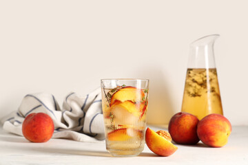 Glass and jug of fresh peach lemonade with thyme on white background