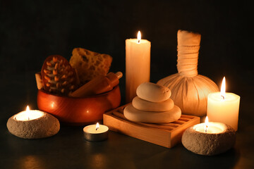 Composition with spa stones, burning candles and herbal bag on black background, closeup