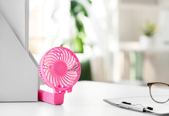 Small electric fan on table in office