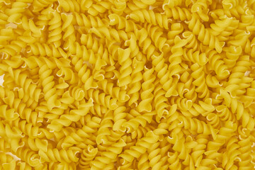 Full image of raw fusilli pasta, with a patterned background and copy space