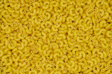 Full image of raw macaroni or elbow pasta, with a patterned background and copy space.