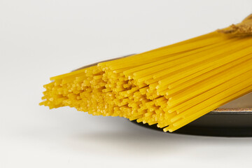 Raw spaghetti in a bundle tied with string on a white background with copy space, traditional Italian pasta.