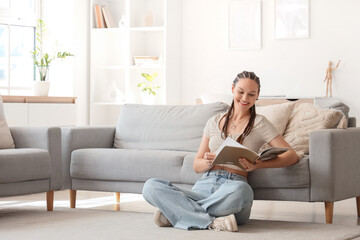 Young woman with dreadlocks reading magazine at home