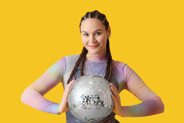 Fashionable young woman with dreadlocks and disco ball on yellow background