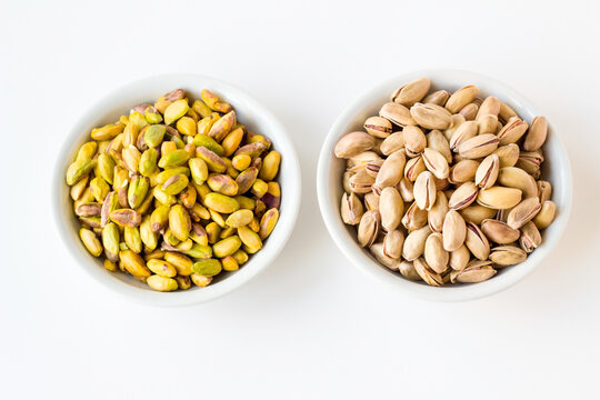 Fresh,crunchy shelled and unshelled pistachios in white color bowls on the white surface,top view