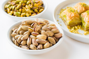 Fresh,crunchy shelled and unshelled pistachios in white color bowls on the white surface with Turkish Baklava