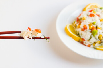 Rice salad or pilaf with colorful vegetables from Asian cuisine.,served with sliced lemon and chopsticks