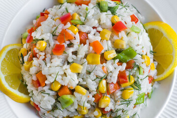 Rice salad or pilaf with colorful vegetables from Asian cuisine.,served with sliced lemon,top view