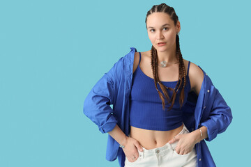 Stylish young woman in shirt with dreadlocks on blue background