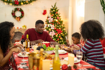 A warm Christmas family dinner with a father serving food to his young child, surrounded by festive decorations, a Christmas tree, and a holiday table spread. Joyful and cozy holiday atmosphere.
