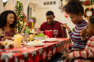 A warm Christmas family dinner with a father serving food to his young child, surrounded by festive decorations, a Christmas tree, and a holiday table spread. Joyful and cozy holiday atmosphere.