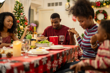 A warm Christmas family dinner with a father serving food to his young child, surrounded by festive decorations, a Christmas tree, and a holiday table spread. Joyful and cozy holiday atmosphere.