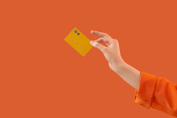 Female hand with credit card on orange background