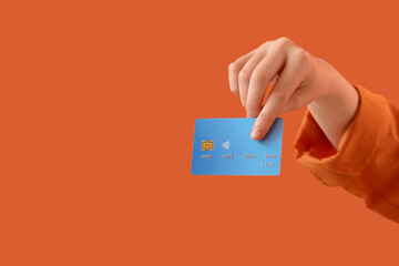 Female hand with credit card on orange background