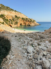 Scenic coastal view with rocky terrain and clear blue water at a secluded beach