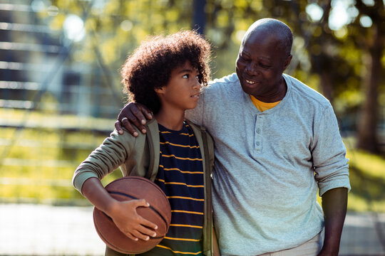 Grandfather and grandson bonding on basketball court outdoors - Powered by Adobe