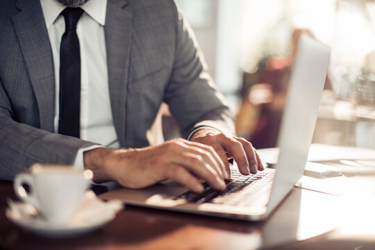 Close up of businessman hands typing on laptop keyboard at cafe table