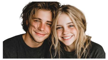A smiling young man and woman pose closely together, their faces illuminated by a bright light, expressing joy and connection.