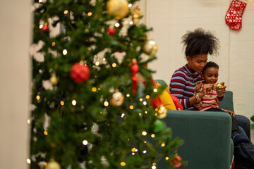 An African American family gathers for a festive Christmas party, enjoying snacks, drinks, and...