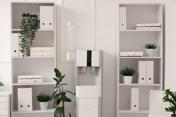 Shelving units with folders, houseplants and water cooler in office