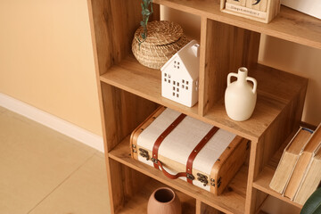 Shelving unit with books and different decor near beige wall in living room, closeup