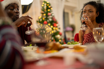 An African American family gathers for a festive Christmas party, enjoying snacks, drinks, and laughter in their decorated living room. Concept for holiday entertaining and joyful feasts.
