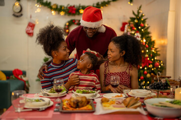An African American family gathers for a festive Christmas party, enjoying snacks, drinks, and laughter in their decorated living room. Concept for holiday entertaining and joyful feasts.