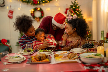 An African American family gathers for a festive Christmas party, enjoying snacks, drinks, and laughter in their decorated living room. Concept for holiday entertaining and joyful feasts.