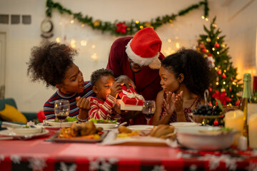 An African American family gathers for a festive Christmas party, enjoying snacks, drinks, and laughter in their decorated living room. Concept for holiday entertaining and joyful feasts.