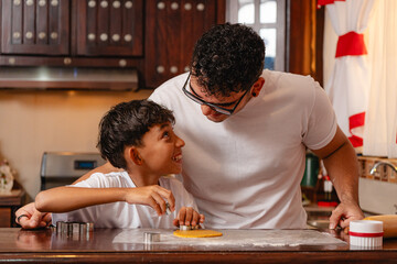 Father and son smiling while cutting cookie dough together