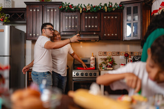 Family baking Christmas cookies and taking selfies in decorated kitchen - Powered by Adobe