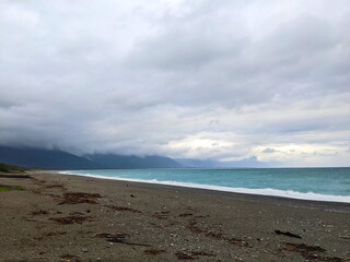 Qixingtan Beach with no people facing the wavy Pacific Ocean on a stormy day while clouds hovering on top of mountains at the back during the pandemic