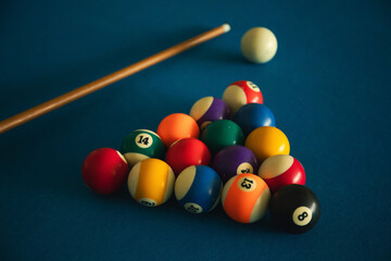 Billiard balls set for a game on a blue felt table with a cue
