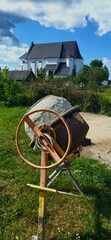 Old construction tools A cement mixer and a church stand together in a rural landscape during a...