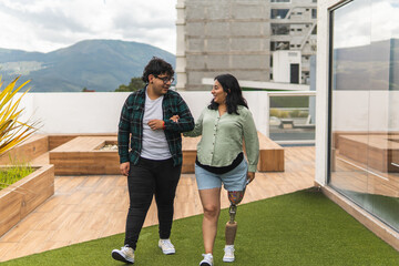 A young man supports his disabled pregnant wife as she walks through a rooftop garden.