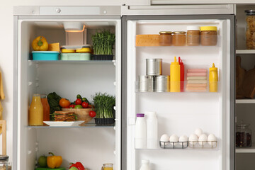Open fridge with products in light kitchen