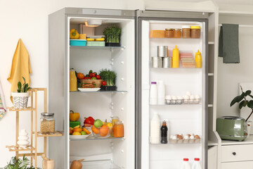 Open fridge with products in light kitchen