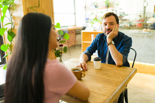 Bored man ignoring his girlfriend at the coffee shop