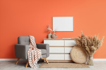 Interior of living room with armchair, commode and blank frame