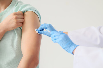 Doctor disinfecting man's arm before vaccination man in clinic, closeup