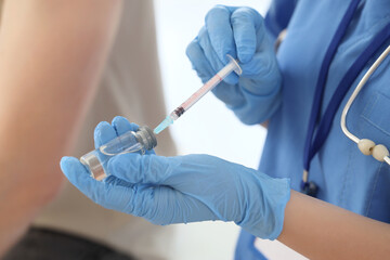 Doctor with vaccine and syringe against man in clinic, closeup