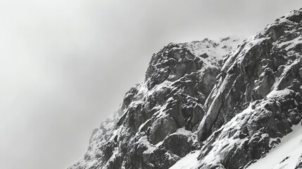 Obraz premium Snow-covered rocky mountain peak under a cloudy sky with rugged cliffs and steep slopes.
